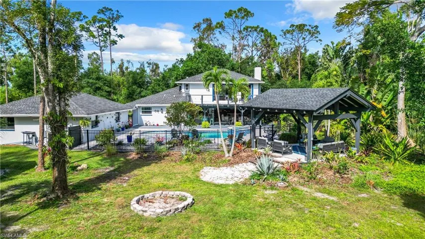 Rear view of property with an outdoor living space with a fire pit, a patio area, a pavillion and a mancured landscape