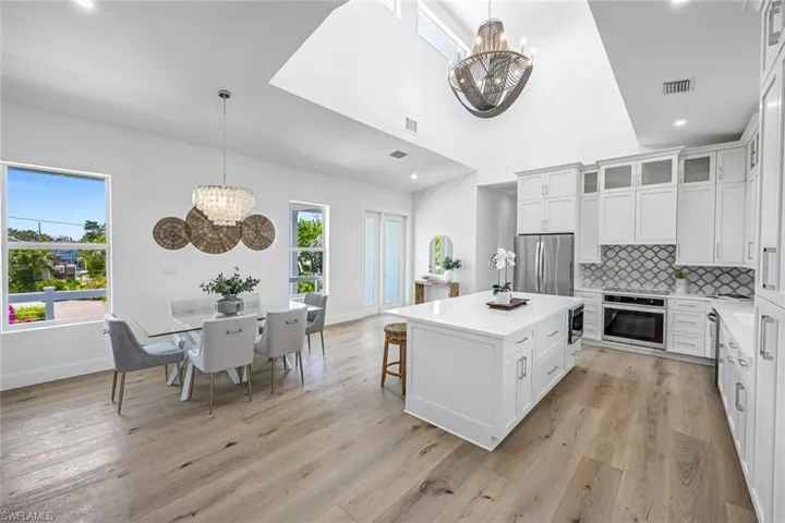 Kitchen featuring appliances with stainless steel finishes, a chandelier, light countertops, light wood-style floors, and backsplash