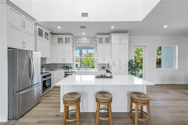 Kitchen with stainless steel appliances, a breakfast bar, recessed lighting, a kitchen island, and decorative backsplash