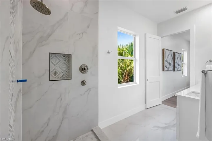 Bathroom featuring a marble finish shower, vanity, baseboards, and marble finish flooring