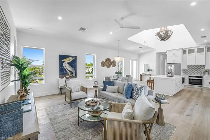 Living area with a chandelier, ceiling fan, light wood-type flooring, recessed lighting, and baseboards