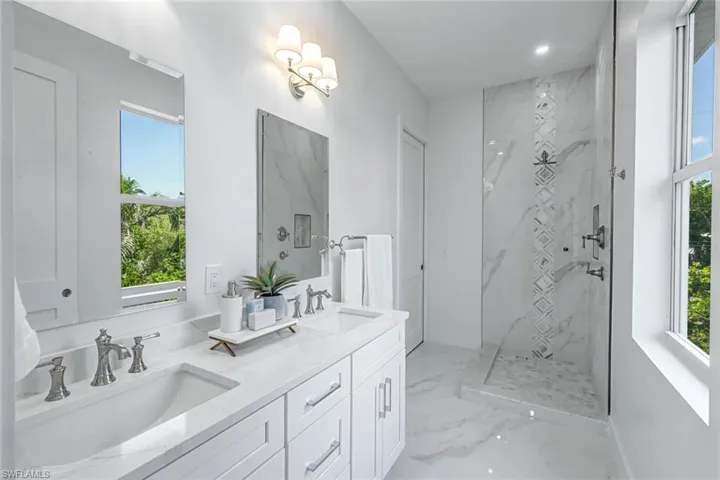 Full bath with marble tiled flooring, double vanity, a marble finish shower, healthy amount of natural light, and recessed lighting
