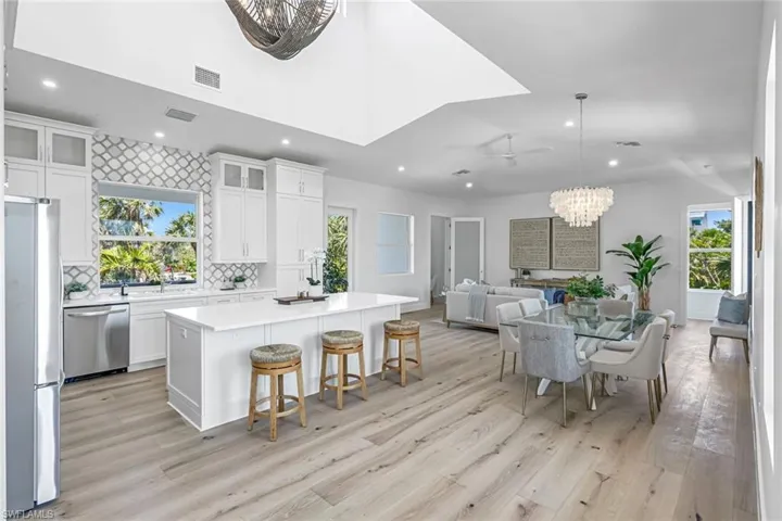 Kitchen featuring stainless steel appliances, light wood finished floors, a chandelier, a center island, and open floor plan