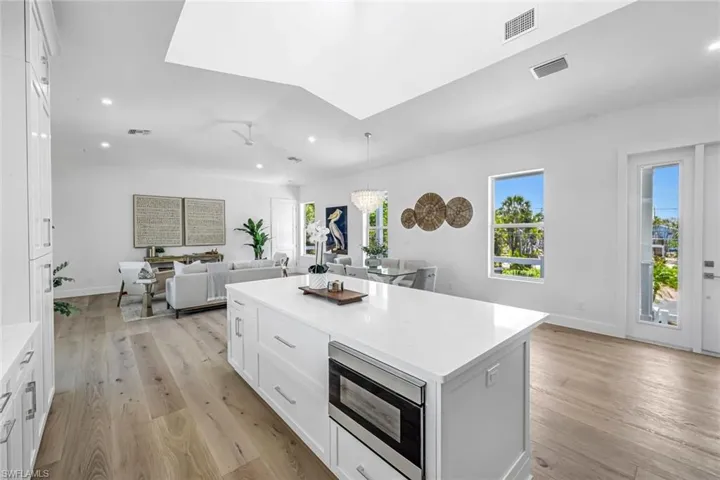 Kitchen featuring stainless steel microwave, a kitchen island, open floor plan, recessed lighting, and light countertops