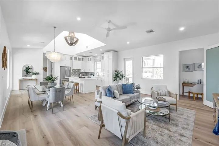 Living room featuring a ceiling fan, a chandelier, light wood-style floors, lofted ceiling, and baseboards