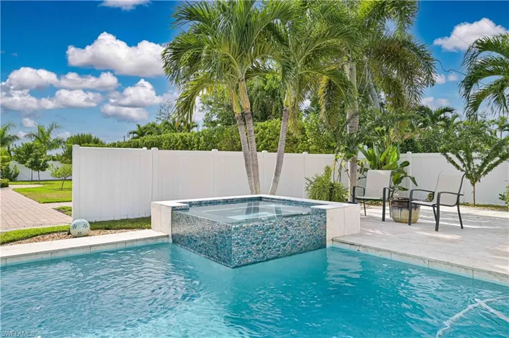 View of pool featuring a patio, a fenced backyard, and a pool with connected hot tub
