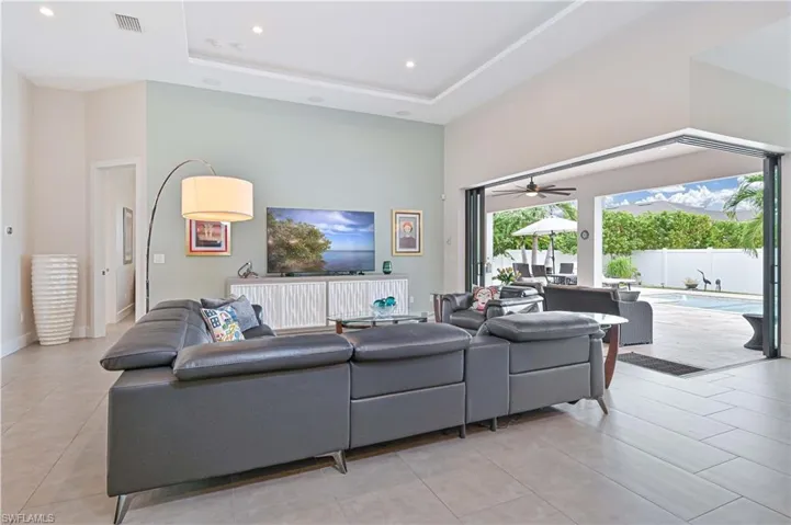 Living room with a towering ceiling, recessed lighting, ceiling fan, a tray ceiling, and light tile patterned flooring
