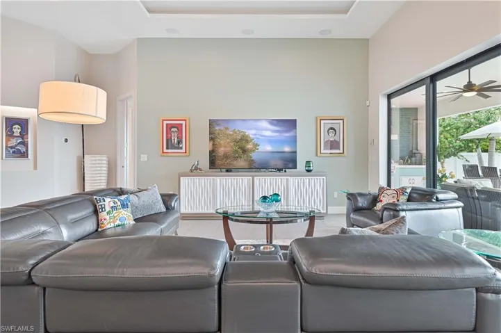 Living area featuring ceiling fan, tile patterned floors, a towering ceiling, and a tray ceiling