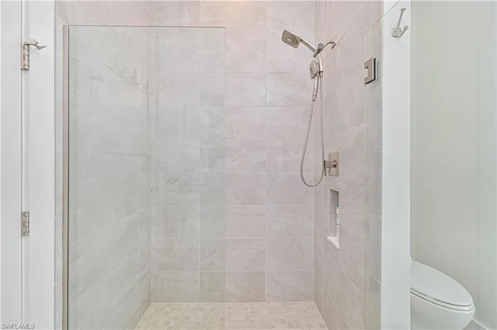 Full bath featuring tiled shower and toilet