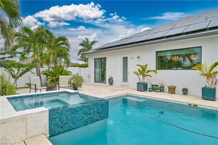 View of swimming pool with a patio, a pool with connected hot tub, and a fenced backyard