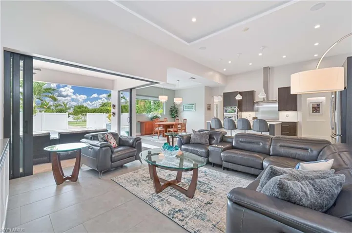 Living area featuring recessed lighting, light tile patterned floors, and a towering ceiling