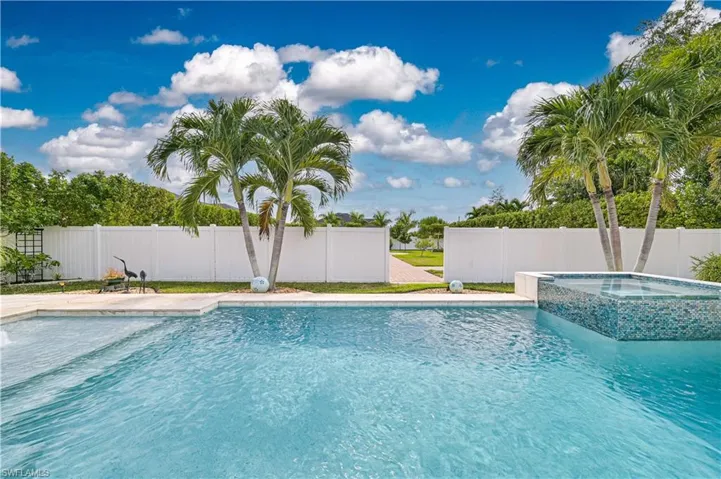 View of pool with a fenced backyard, a pool with connected hot tub, and a patio