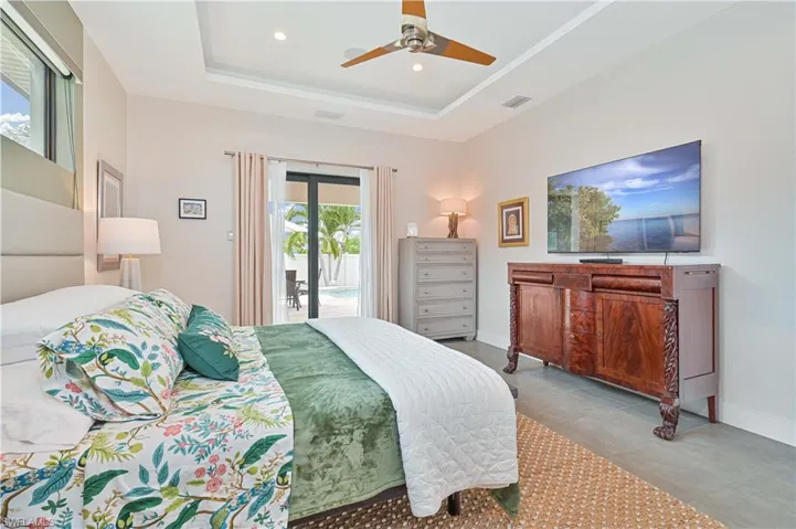Bedroom with access to outside, ceiling fan, a raised ceiling, and recessed lighting