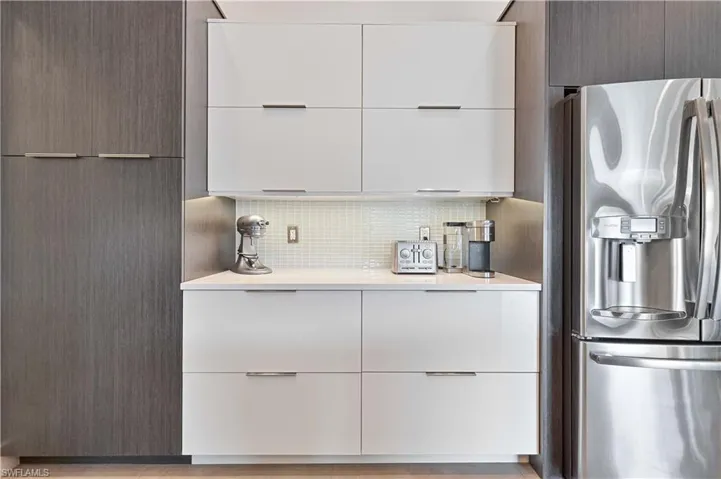 Kitchen featuring modern cabinets, stainless steel fridge, white cabinetry, and decorative backsplash