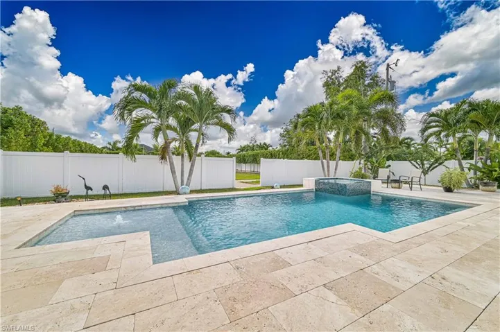 View of pool featuring a patio area, a pool with connected hot tub, and a fenced backyard