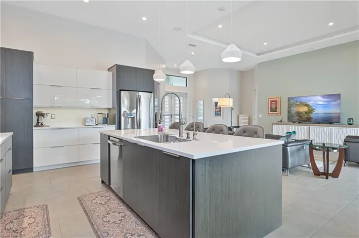 Kitchen with white cabinetry, modern cabinets, decorative light fixtures, stainless steel appliances, and backsplash