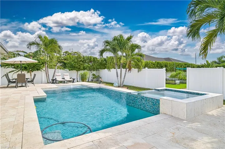 View of swimming pool featuring a patio area, a fenced backyard, and a pool with connected hot tub