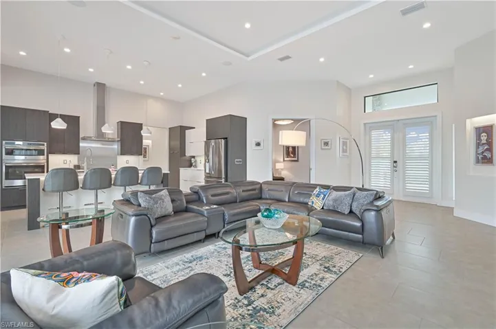 Living area with a towering ceiling, recessed lighting, french doors, and light tile patterned flooring