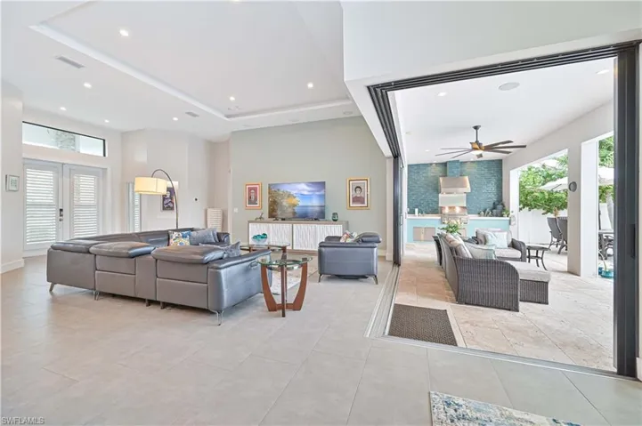 Living room featuring a ceiling fan, french doors, recessed lighting, light tile patterned floors, and a towering ceiling