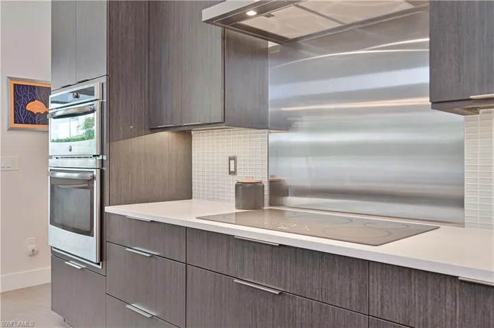 Kitchen with tasteful backsplash, stainless steel double oven, black electric cooktop, modern cabinets, and extractor fan