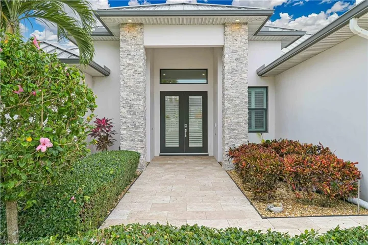 View of exterior entry with stucco siding, stone siding, and french doors