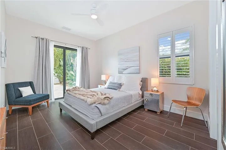 Bedroom with wood tiled floors, access to exterior, ceiling fan, and multiple windows