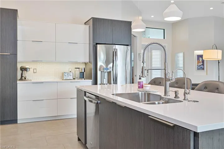 Kitchen featuring modern cabinets, white cabinetry, backsplash, stainless steel fridge, and recessed lighting