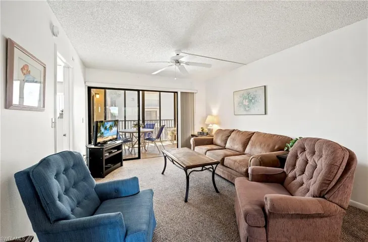 Carpeted living room with a textured ceiling and ceiling fan