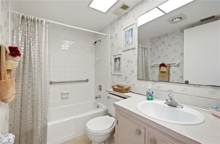 Full bathroom featuring toilet, vanity, shower / bath combo with shower curtain, and visible vents