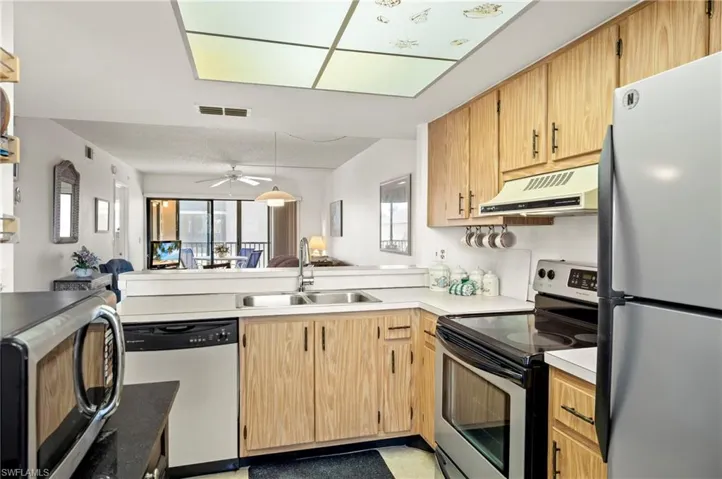 Kitchen featuring visible vents, a sink, ventilation hood, open floor plan, and appliances with stainless steel finishes