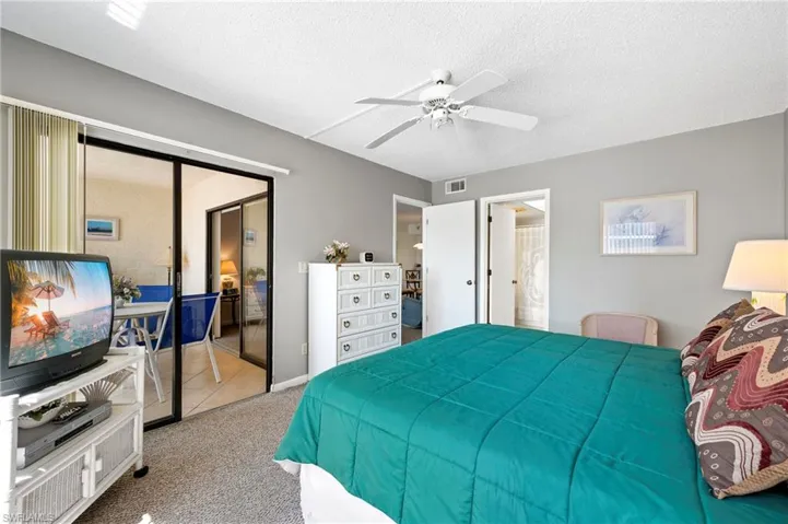 Carpeted bedroom with tile patterned floors on sunroom, visible vents, a textured ceiling, and ceiling fan