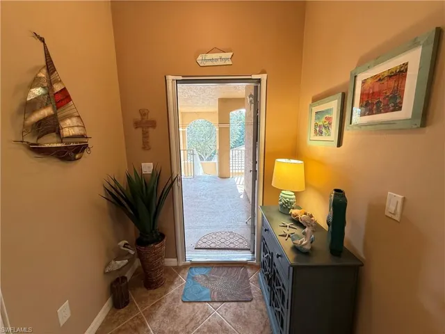 Doorway with tile patterned floors and baseboards