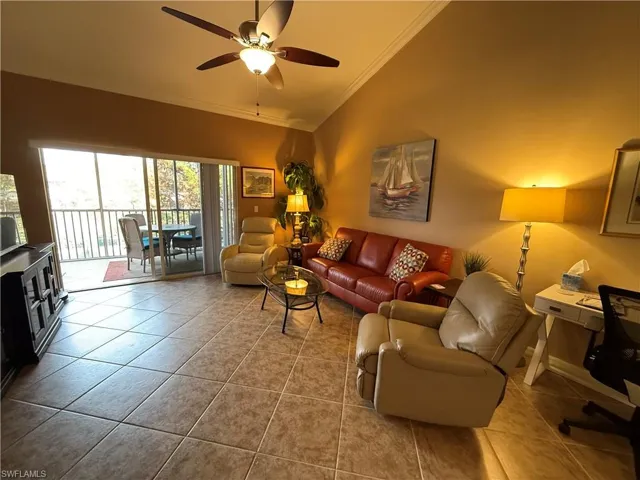 Tiled living area with ornamental molding, a ceiling fan, an office area, and lofted ceiling