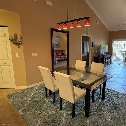 Tiled dining space with high vaulted ceiling and ornamental molding