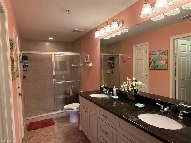 Full bathroom with a shower stall, double vanity, and light tile patterned flooring