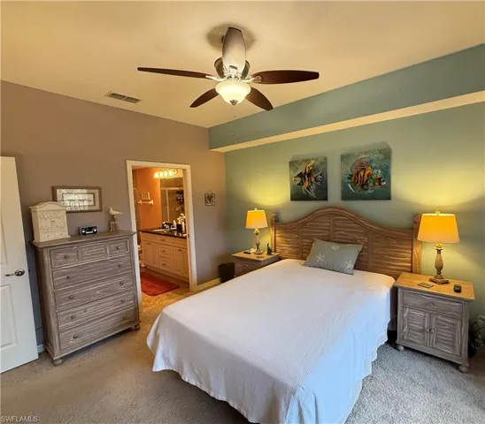 Bedroom with light carpet, ceiling fan, and ensuite bathroom