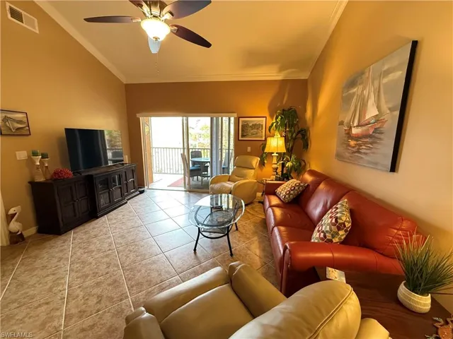 Living room with crown molding, tile patterned floors, and a ceiling fan