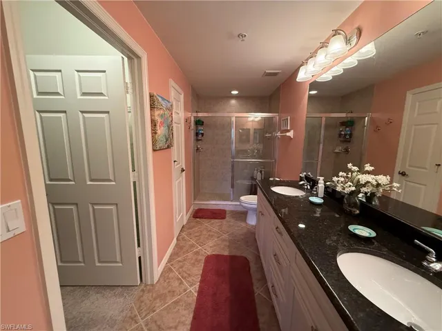 Full bath with double vanity, a stall shower, and light tile patterned floors