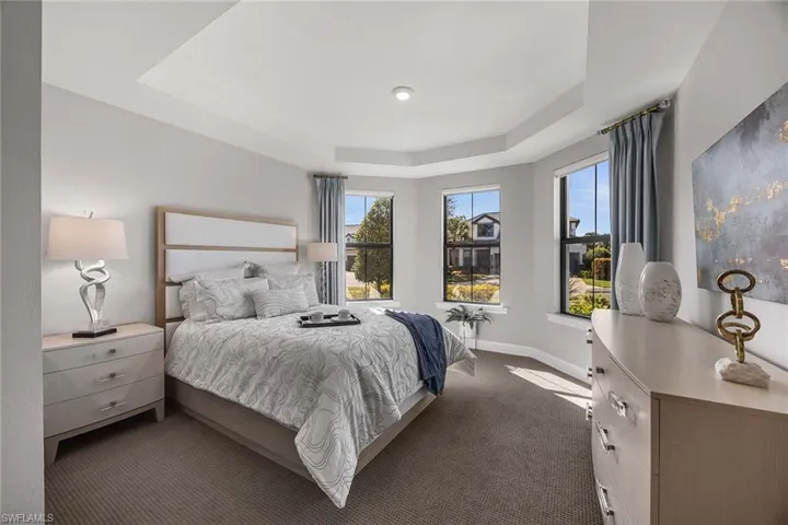 Carpeted bedroom featuring a raised ceiling and baseboards