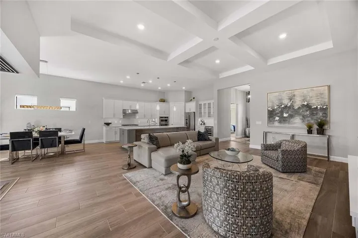 Living area with coffered ceiling, beam ceiling, light wood-type flooring, and recessed lighting