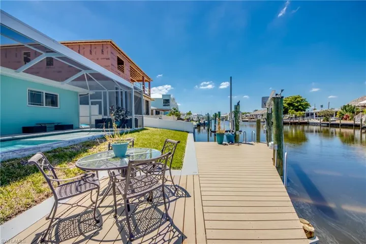 Dock area with a water view, a lanai, and a lawn