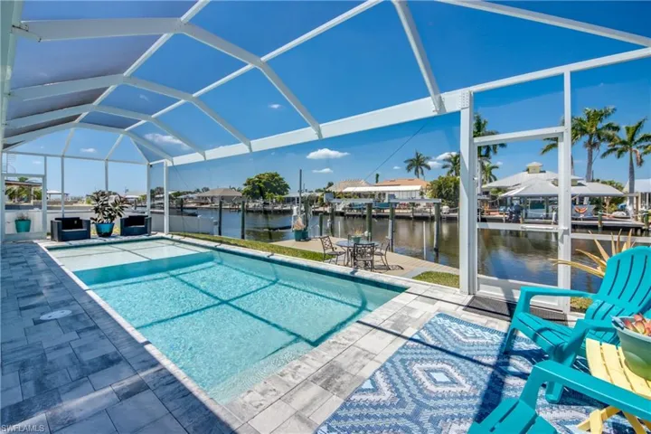 View of swimming pool with a lanai, a dock, a water view, and a patio