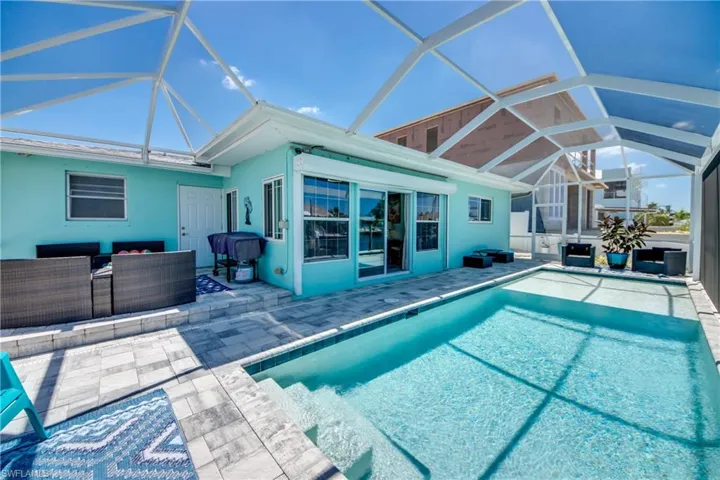 View of swimming pool with glass enclosure and a patio