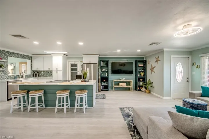Kitchen with backsplash, a breakfast bar, white cabinets, and appliances with stainless steel finishes