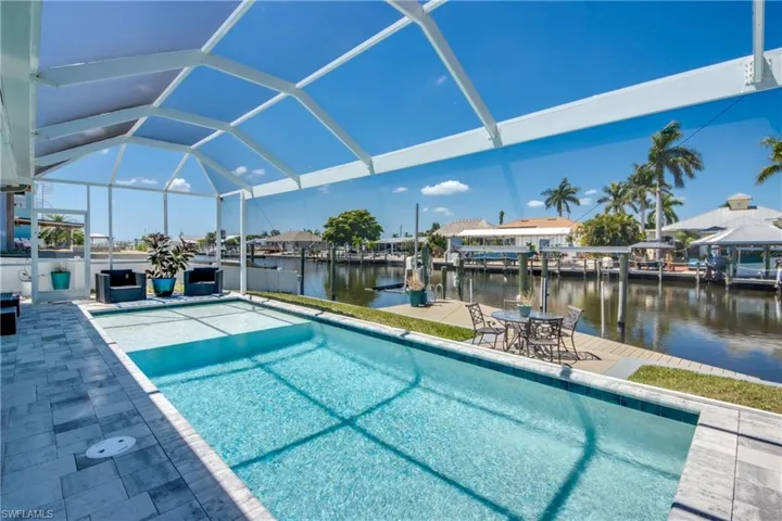 View of swimming pool with a dock, a water view, a patio area, and a lanai