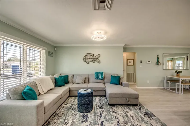 Living room featuring wood-type flooring and crown molding
