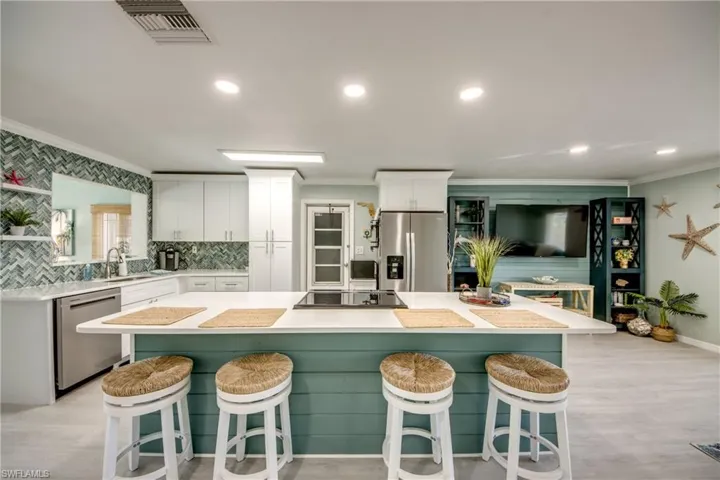 Kitchen with a kitchen bar, stainless steel appliances, white cabinetry, and a kitchen island