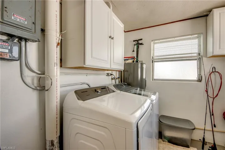 Clothes washing area featuring cabinets, a textured ceiling, separate washer and dryer, and gas water heater
