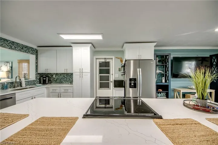 Kitchen with light stone countertops, sink, white cabinetry, and stainless steel appliances