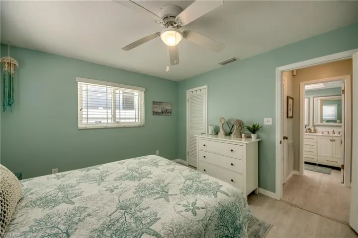 Bedroom with ceiling fan, light hardwood / wood-style floors, a textured ceiling, and a closet